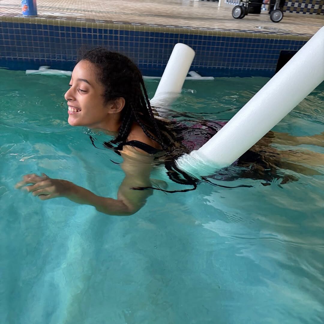 Aquatic physical therapy session in the pool with a pool noodle.