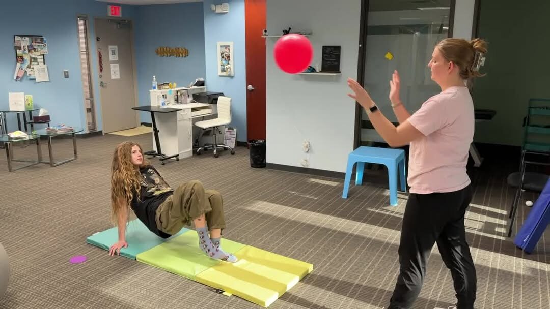 A child doing a crab-march exercise modified to tap a balloon.